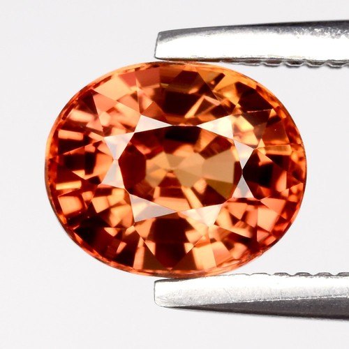 Orange oval sapphire held in tweezers