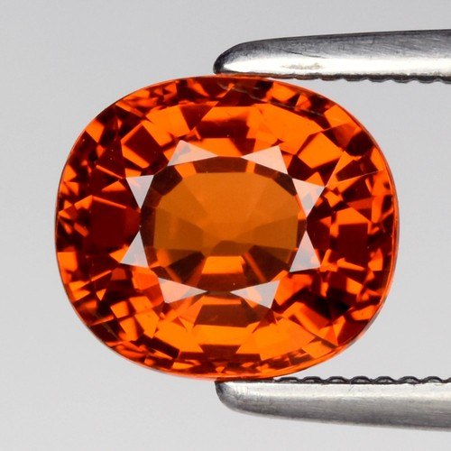 Orange cushion spessartite garnet held in tweezers